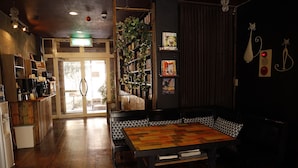 A cozy cafe with a wooden table, shelves with books, and a door leading outside.