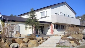 A two-story house with a flat roof, large windows, and a stone foundation.