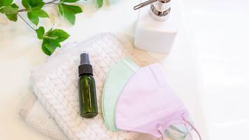 Un lavamanos con una botella verde, una mascarilla rosa y un dispensador de jabón blanco.