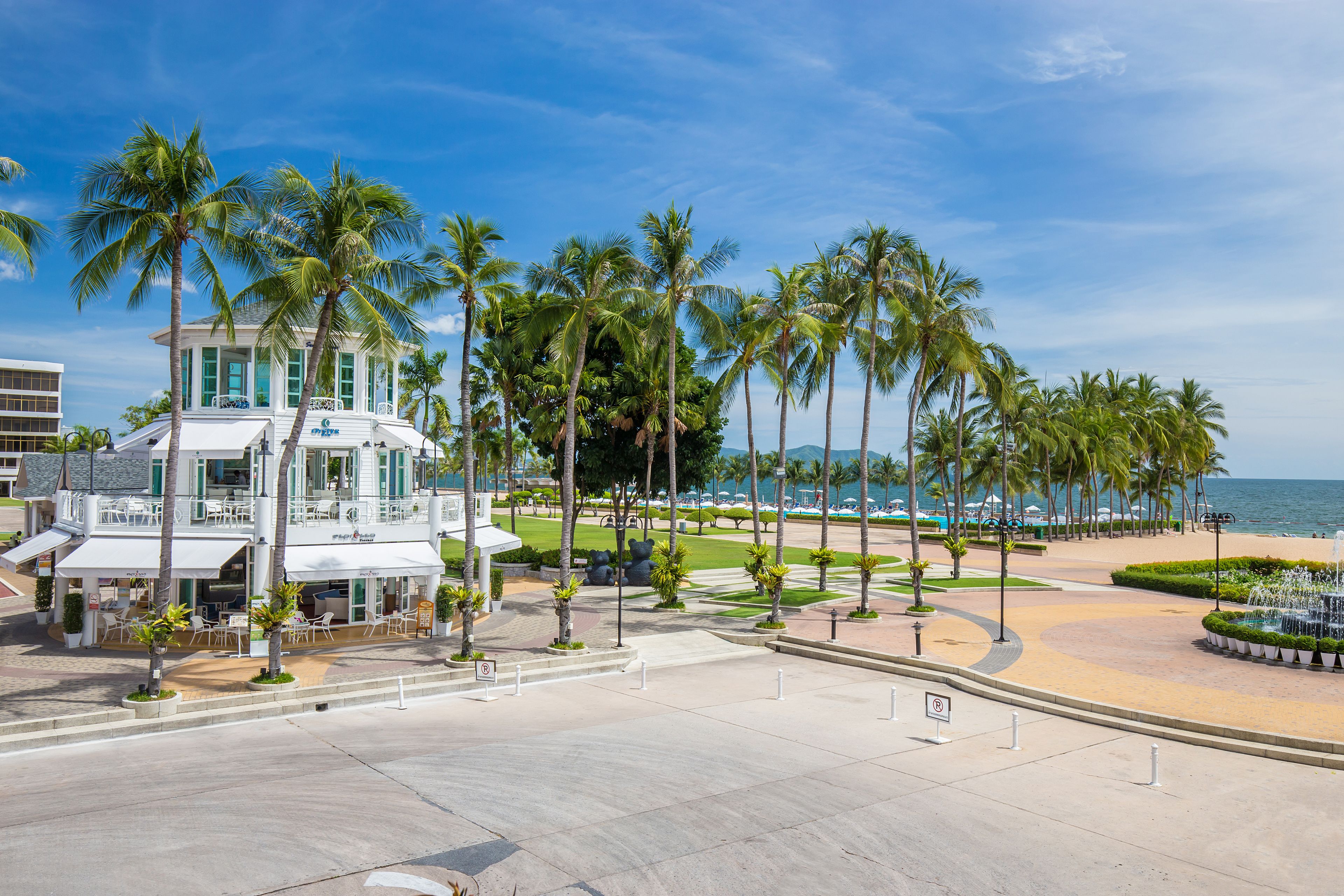 Un hôtel situé en bord de mer, doté d’une piscine, de palmiers et offrant une vue sur l’océan.