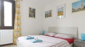 A bedroom with a bed, a nightstand, a window with curtains, and three framed pictures on the wall. - Mario Apartment 2 (Venice)