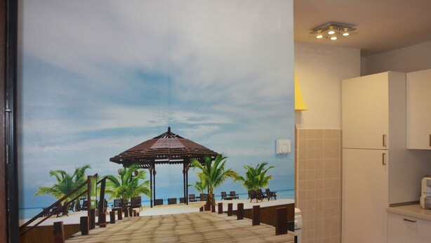 A beach-themed mural with a wooden deck, palm trees, and a gazebo. - Mario Apartment 2 (Venice)