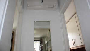 A hallway with a white air conditioning unit mounted on the wall, leading to a room with a wardrobe and a door. - Mario Apartment 2 (Venice)