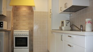 A kitchen with a white stove, white cabinets, and a microwave. - Mario Apartment 2 (Venice)