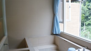 Un baño con bañera, una ventana con cortina y vistas al exterior.