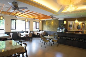 Ein Restaurant mit Holzbalken, Deckenventilatoren und einer Bar.
