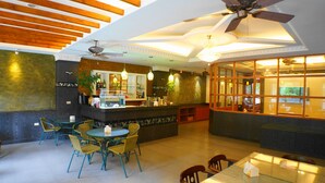 Un restaurante con zona de bar, techo de madera y sillas verdes.
