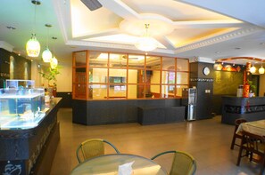 A restaurant with a glass counter, wicker chairs, and a chandelier. - Ying Su Health Spa Hotel (Ren'ai)