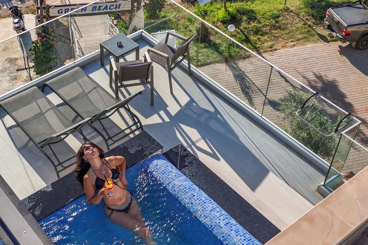 A rooftop pool area with a glass balustrade, a table, and chairs.