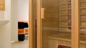 Ein Holzkleiderschrank mit Glastüren, ein weißes Waschbecken und eine schwarze Tasche auf dem Boden.