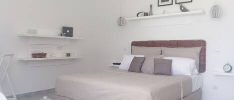 Een moderne slaapkamer met een groot bed, witte muren en een minimalistische inrichting.