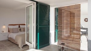 Un dormitorio con cama, puerta corredera y vistas a un espacio exterior con una silla y una mesa.