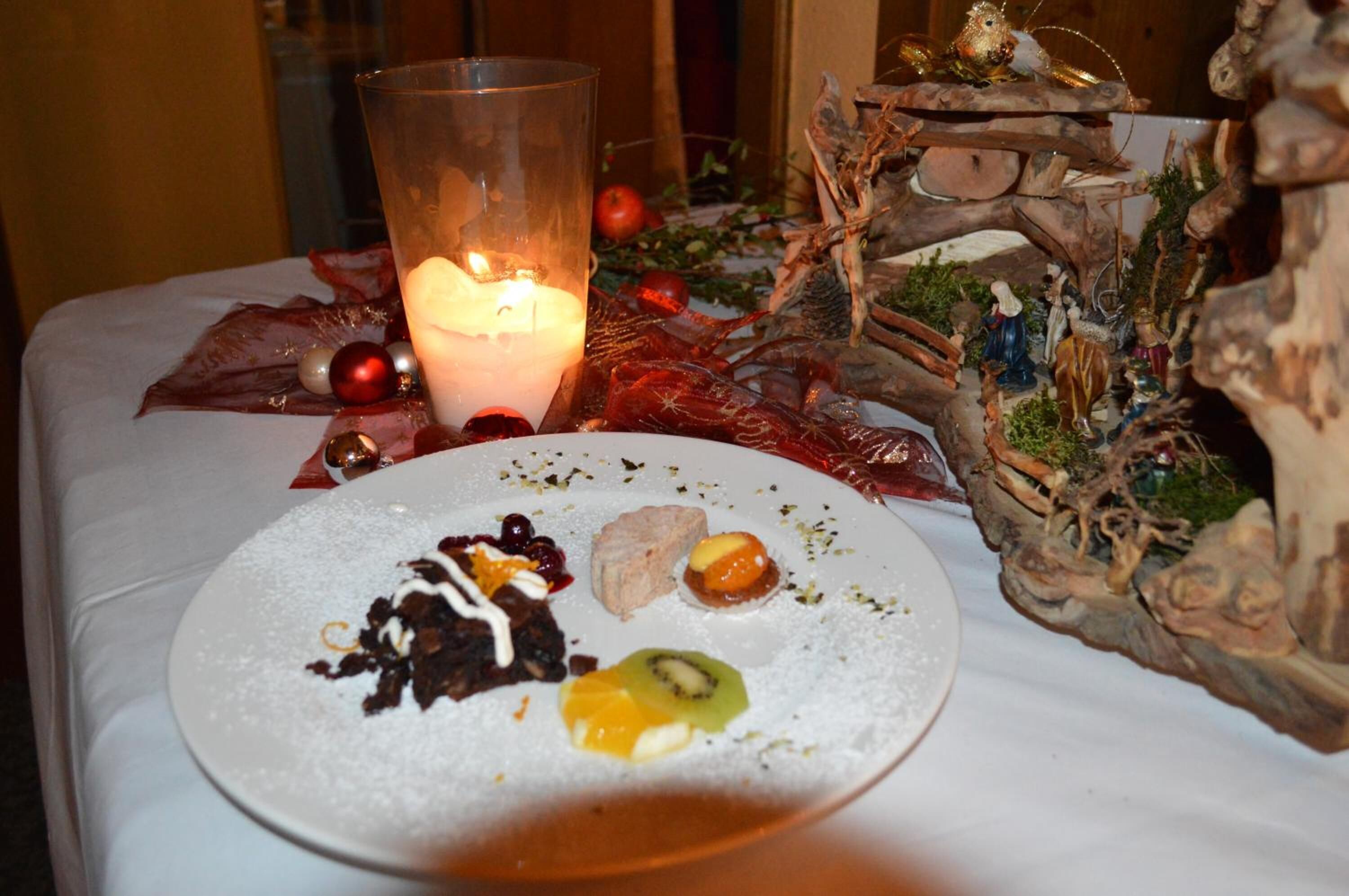 A dessert plate with various sweets and a candle on a table.
