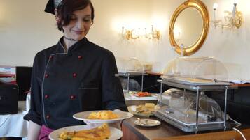 Montaje tipo buffet con diversos alimentos y una persona sirviendo.