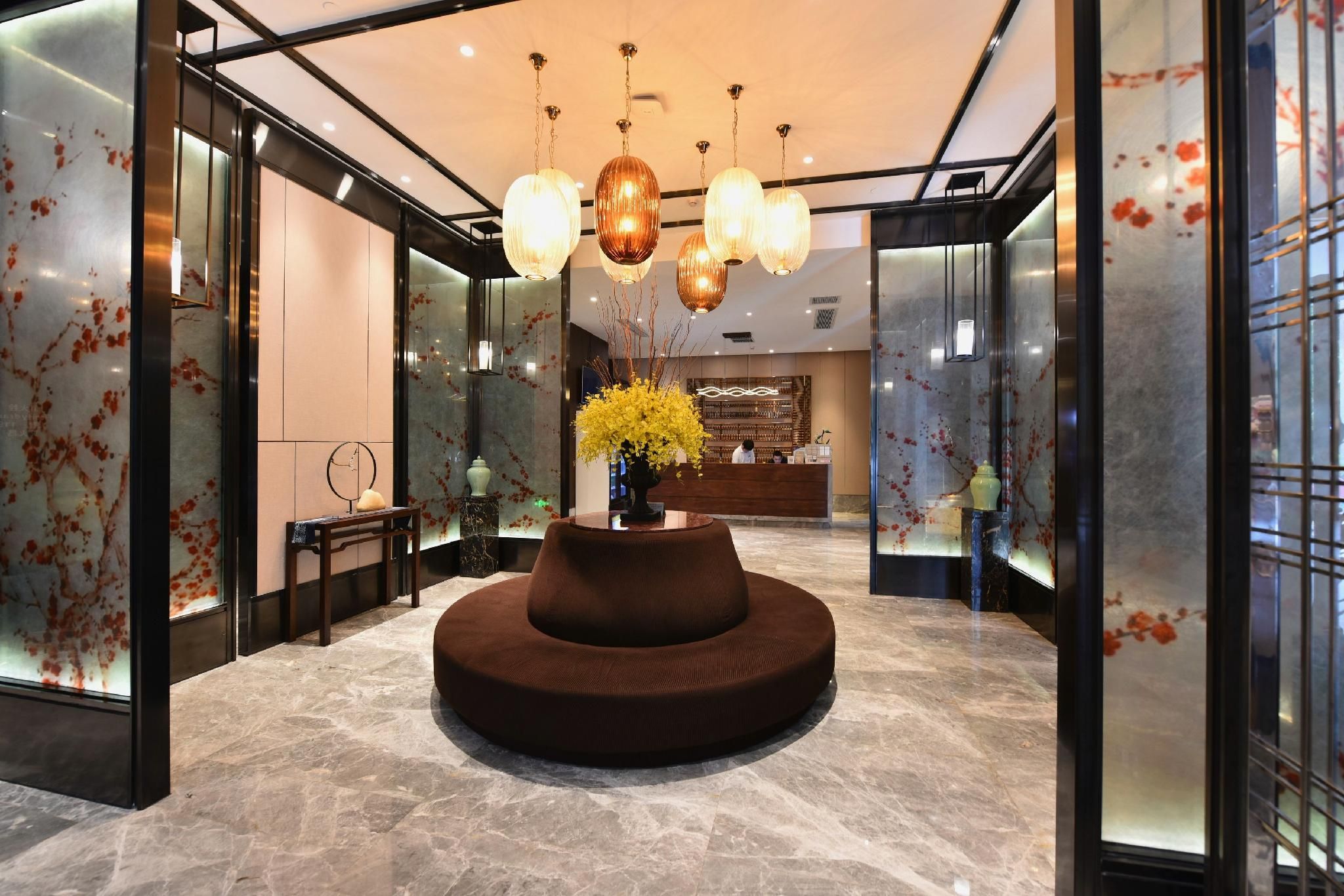 A lobby with a central seating area, a reception desk, and modern lighting fixtures.
