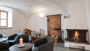 A cozy room with a fireplace, a table with a candle, and comfortable seating. - Hotel Post Bivio (Surses)