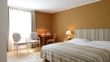 Ein Hotelzimmer mit einem Bett, zwei Stühlen, einem Schreibtisch und einer Lampe.