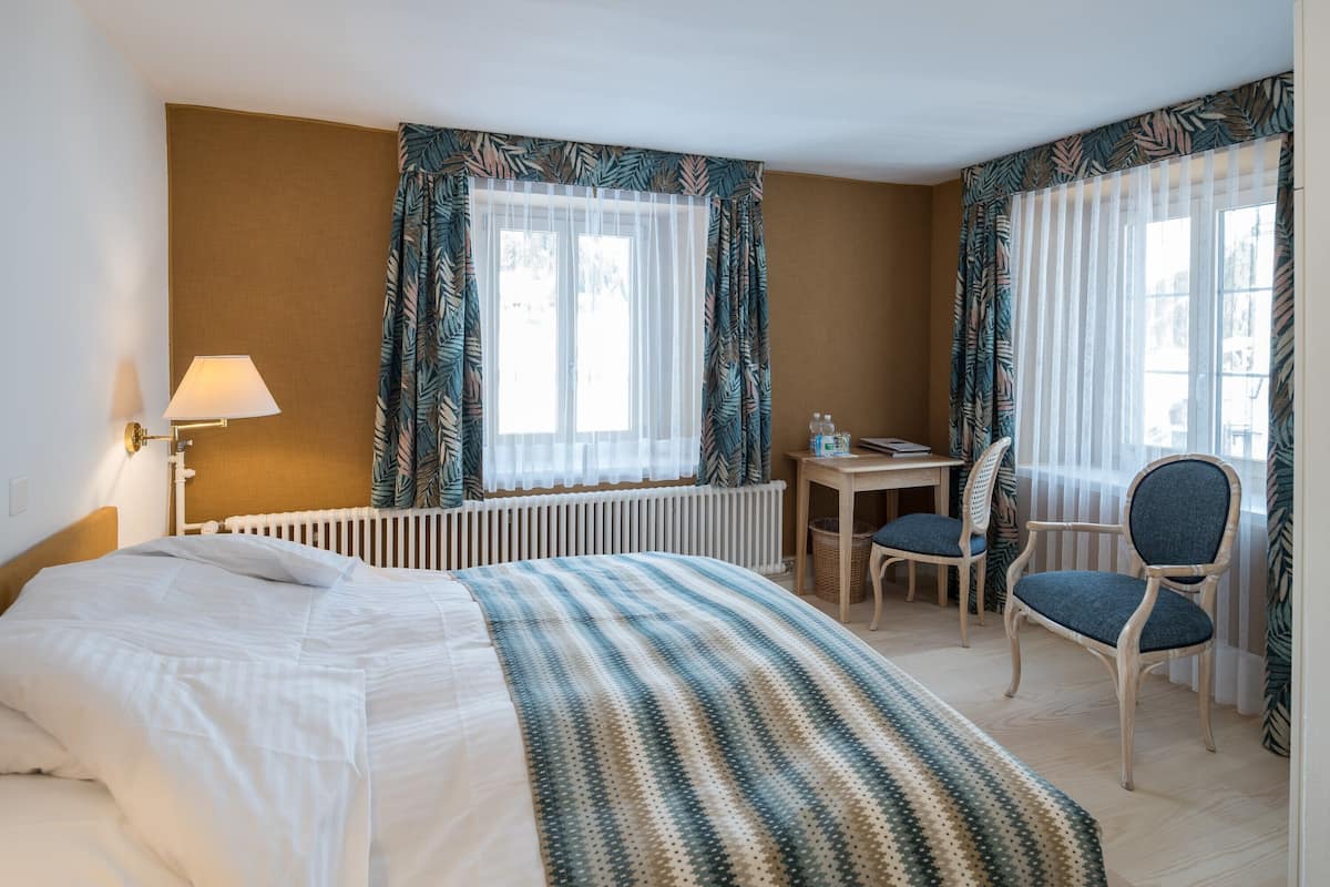 A hotel room with a bed, a desk, and two chairs.