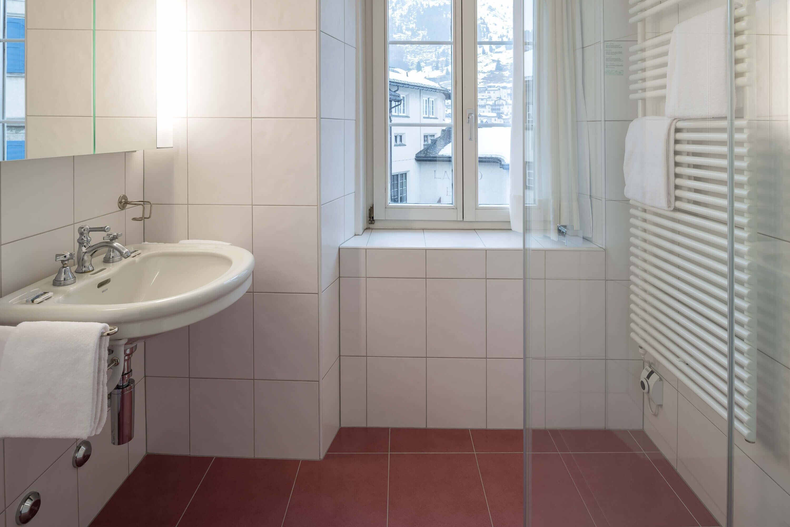 A bathroom with a white sink, a window, and a towel rack.