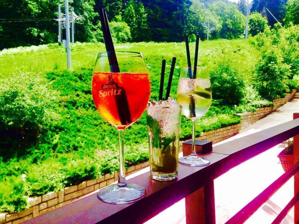 Tres vasos de bebidas en un balcón con vistas a un paisaje verde exuberante.