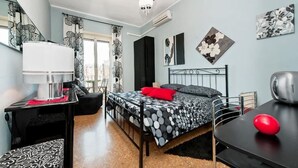 A bedroom with a bed, a desk, a chair, a lamp, and a red object on the desk. - Il Bacio delle Stelle (Rome)