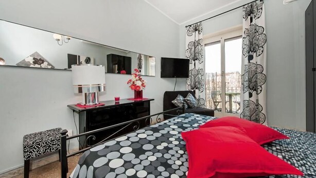 A bedroom with a bed, a dresser, a TV, and a window with curtains. - Il Bacio delle Stelle (Rome)