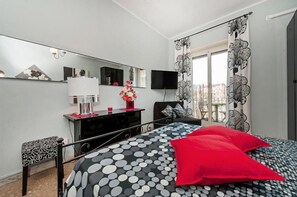 A bedroom with a bed, a dresser, a TV, and a window with curtains. - Il Bacio delle Stelle (Rome)