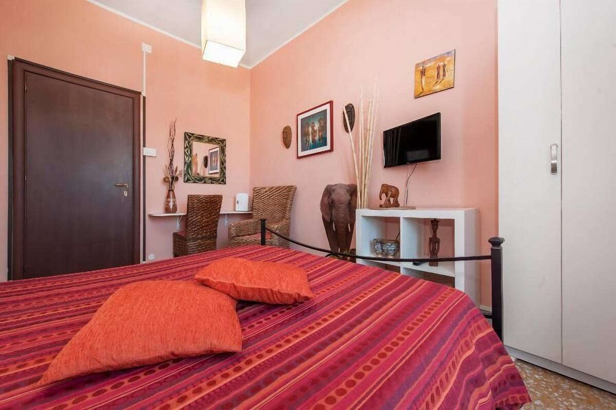A bedroom with a bed, a TV, a wardrobe, and a door.
