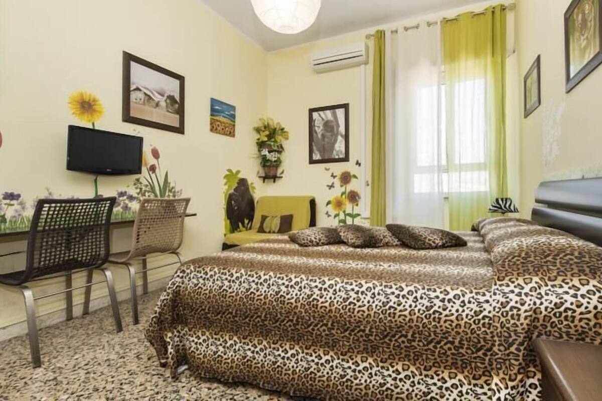 A bedroom with two beds, a desk, a chair, and a TV.