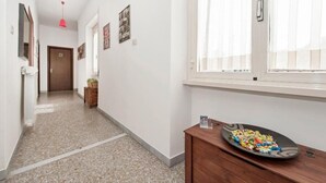 A hallway with a wooden cabinet, a plate of colorful snacks, and a door at the end. - Il Bacio delle Stelle (Rome)