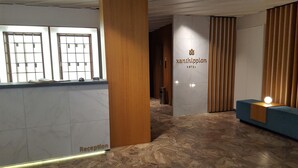 Un área de recepción con piso de mármol, un mostrador de recepción y un cartel que dice 'Xanthippion Hotel'.