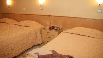 A hotel room with two beds, a nightstand, and wall-mounted lights.