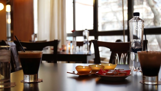 Una mesa con bebidas, velas y una botella de agua en un restaurante.
