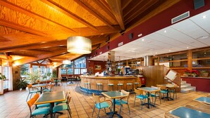 Un restaurante espacioso con altos techos de madera, una zona de bar central y diversas opciones de asientos.