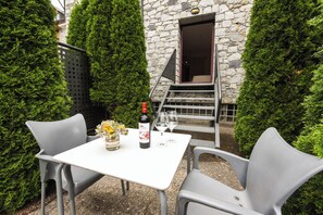A table set outdoors with a bottle of wine, two glasses, and a vase of flowers. - SOMMOS Hotel Benasque Spa (Benasque)