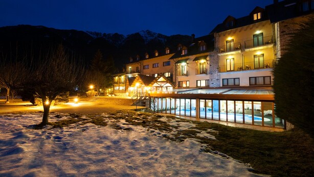 Un hotel de varios pisos, con piscina y un paisaje nevado.
