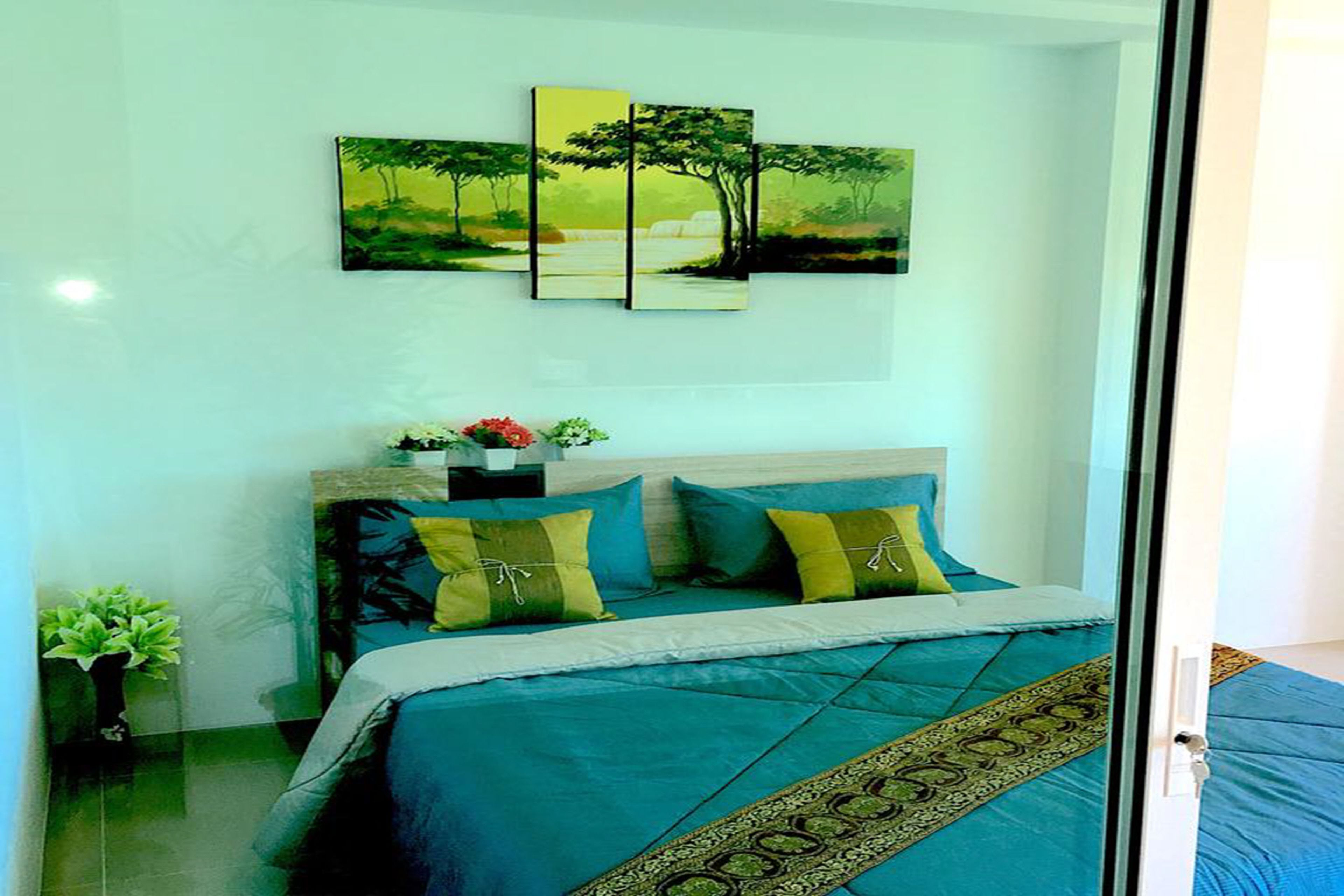 A bedroom with a bed, a nightstand, a potted plant, and a painting on the wall.