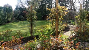 Un jardín con césped, árboles y una pérgola de madera.