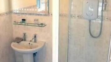A bathroom with a sink, mirror, and shower.