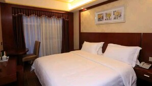 Habitación de hotel con una cama grande, un escritorio con silla, un teléfono y un cuadro en la pared.