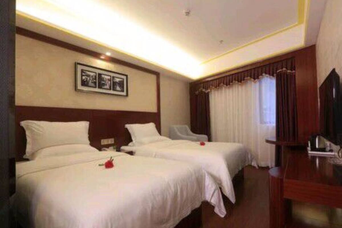 A hotel room with two beds, a desk, and a chair.