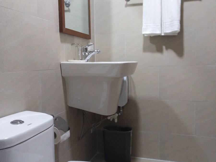 A bathroom with a toilet, sink, mirror, and towel rack.