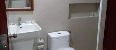 A small bathroom with a toilet, sink, and a mirror.