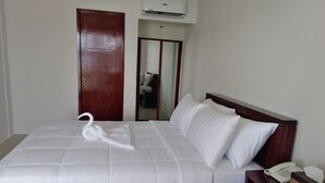 A neatly made bed with a swan-shaped towel, a bedside telephone, and a mirror above the door. - Nirvana Resort (Puerto Galera)