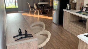 A modern kitchen with wooden cabinets, a dining area with a round table and chairs, and a refrigerator. - Unique Serviced Apartment (Hanoi)