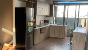 A modern kitchen with wooden cabinets, a stainless steel refrigerator, a microwave, and a sink. - Unique Serviced Apartment (Hanoi)