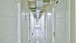 A long, narrow hallway with white doors on both sides, leading to a bright room at the end. - Gökçe Pansiyon - Adult Only - Hostel (Istanbul)