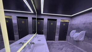 A modern bathroom with a long vanity, multiple urinals, and dark walls. - Gökçe Pansiyon - Adult Only - Hostel (Istanbul)