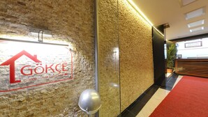 A hotel sign with a red logo and text on a textured wall. - Gökçe Pansiyon - Adult Only - Hostel (Istanbul)