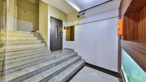 A staircase with marble steps leading to a door, a wall-mounted light fixture, and a wooden panel on the right. - Gökçe Pansiyon - Adult Only - Hostel (Istanbul)